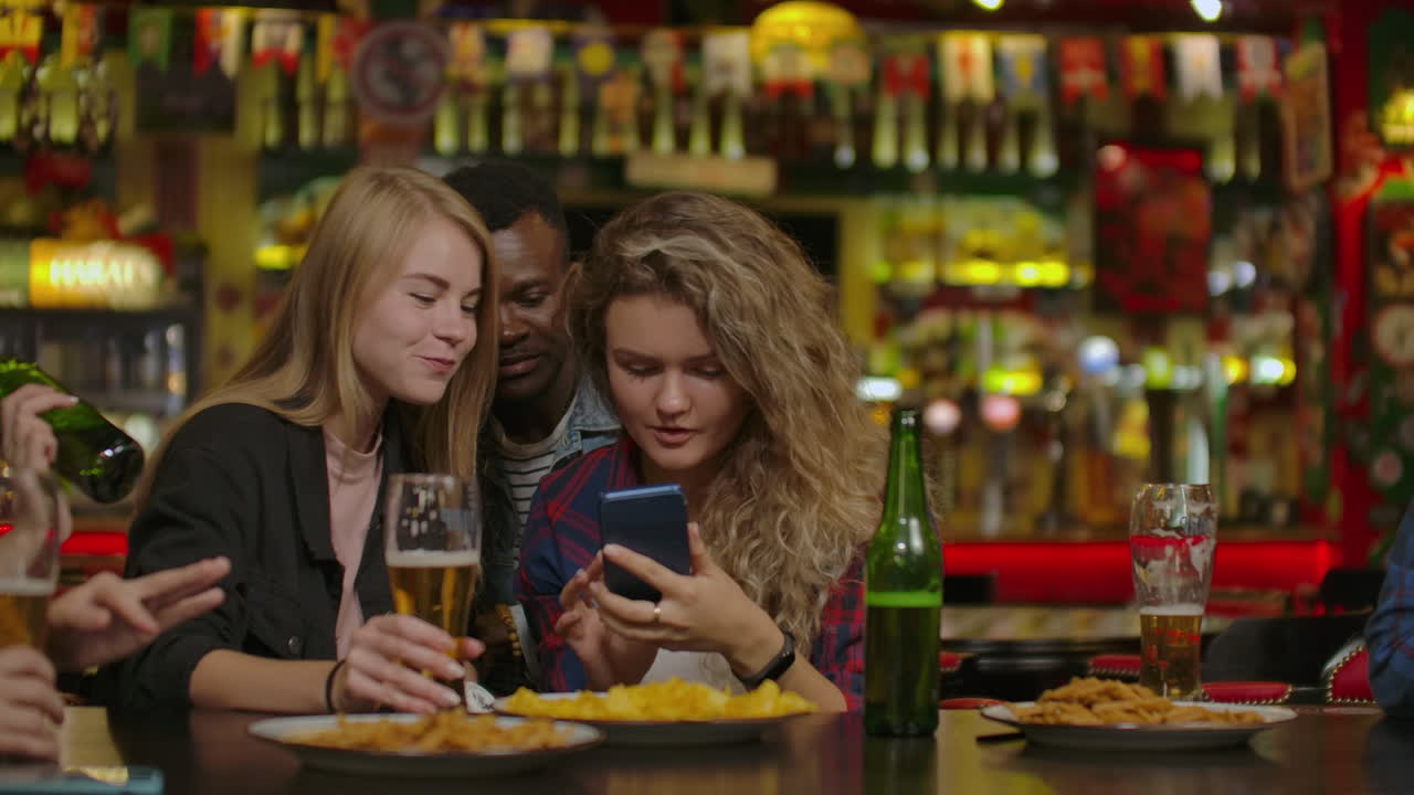 Un gruppo di amici si diverte a guardare una foto sul telefono in uno sport bar.