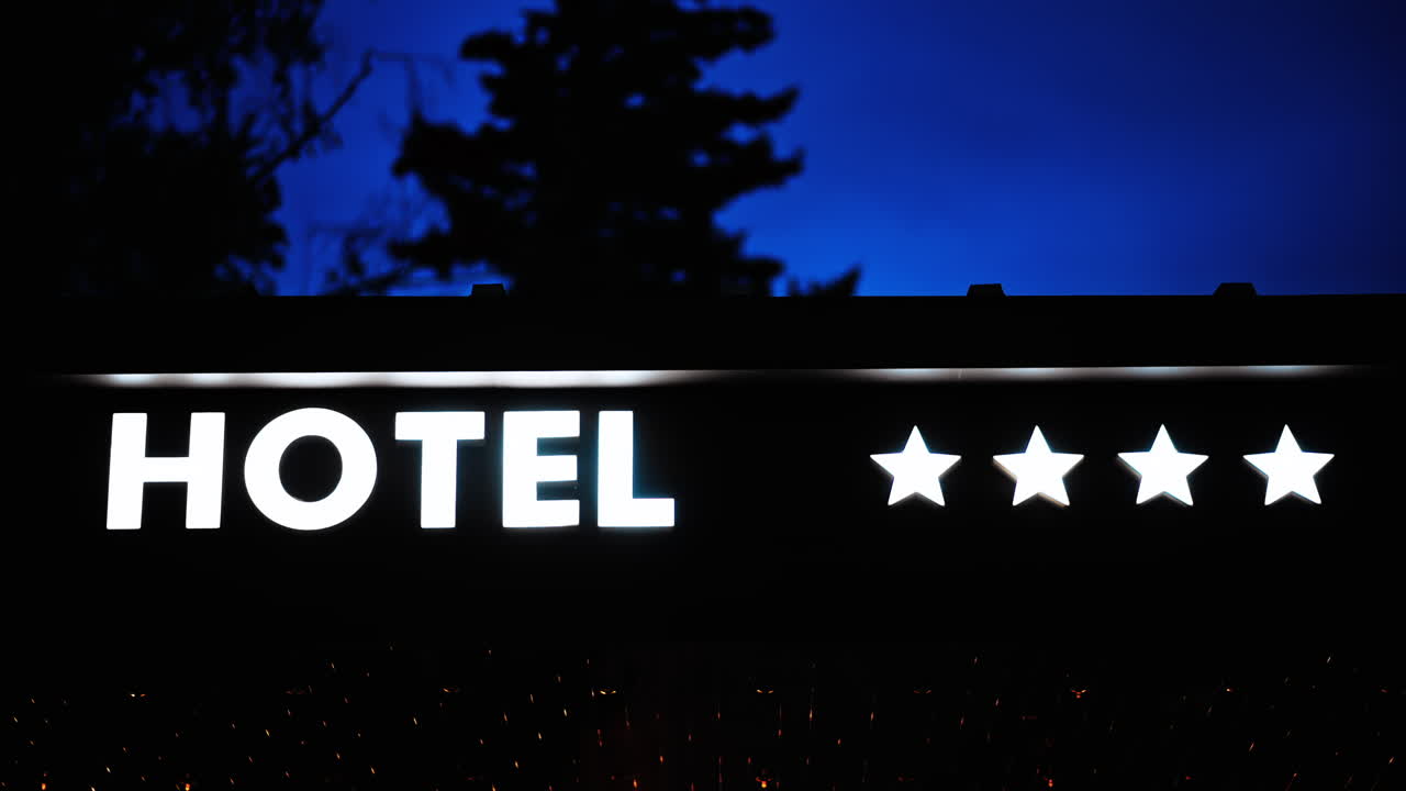 Panneau néon blanc d’hôtel 4 étoiles avec des lumières orange, de nuit