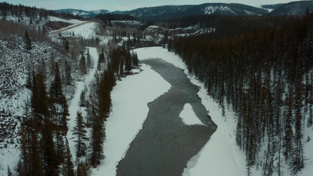 Dronekuva suoraan talvisen puron ja puiden yläpuolelta 4K