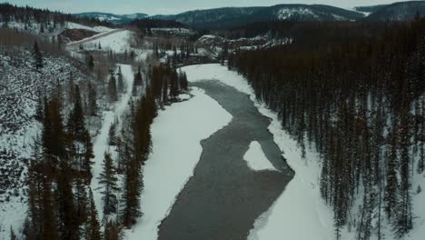 Drone-shot-straight-over-winter-creek-and-trees-4K