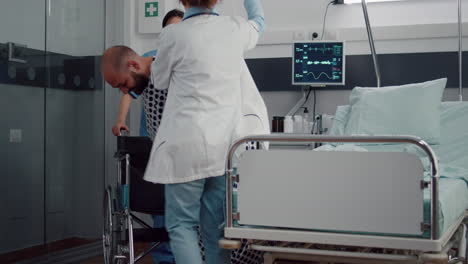 medical team helping sick patient with leg fracture putting in wheelchair