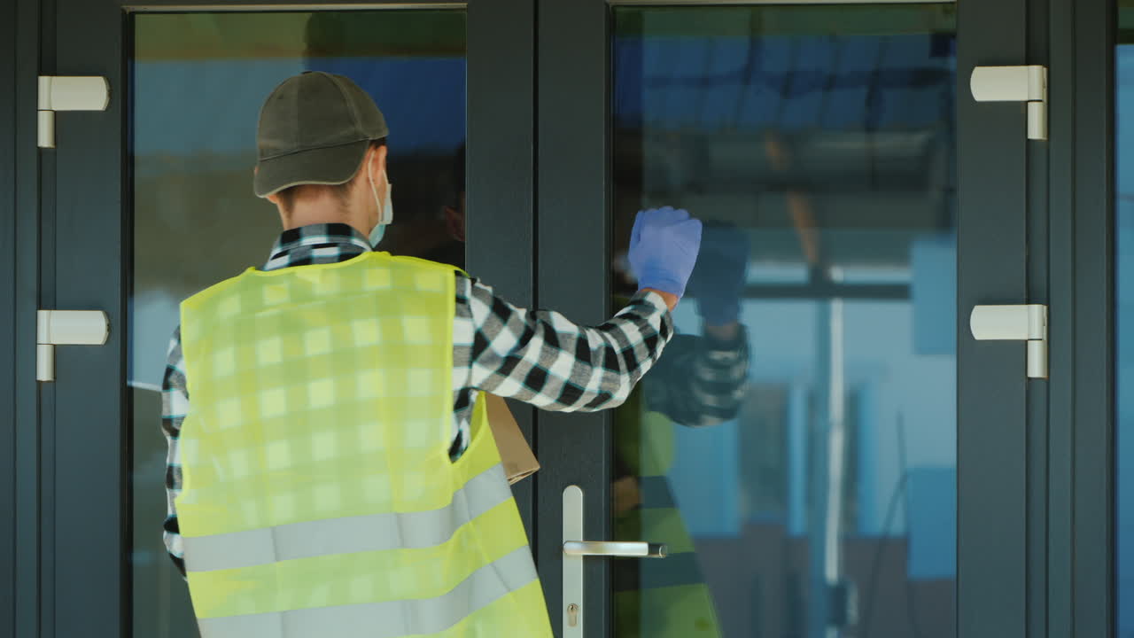 un mensajero con una máscara y guantes protectores entrega un paquete