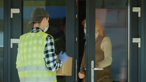 Ein-Kurier-Mit-Maske-Und-Schutzhandschuhen-Liefert-Ein-Paket-Aus