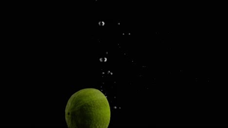 Lime-Falling-into-Water-Super-Slowmotion,-Black-Background,-lots-of-Air-Bubbles,-4k240fps