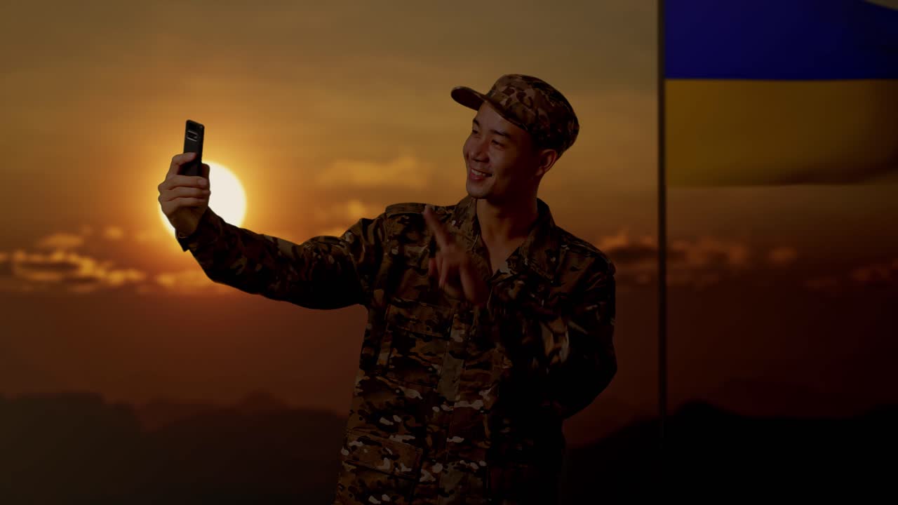 soldado tomando una selfie frente a la bandera ucraniana al atardecer