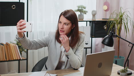 Mujer-De-Negocios-Usando-Videollamadas-De-Grabación-De-Teléfonos-Inteligentes-Para-Redes-Sociales-Posando-Sonriendo-En-La-Mesa-De-La-Oficina