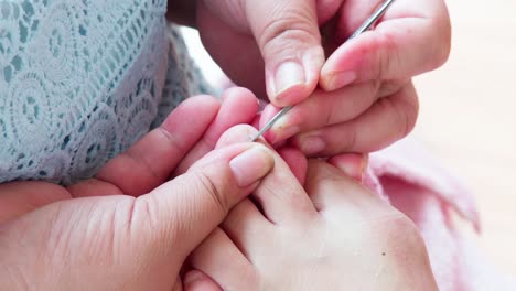 pedicurist master making pedicure cutting cuticle with nail tongs on client's toes in a beauty salon