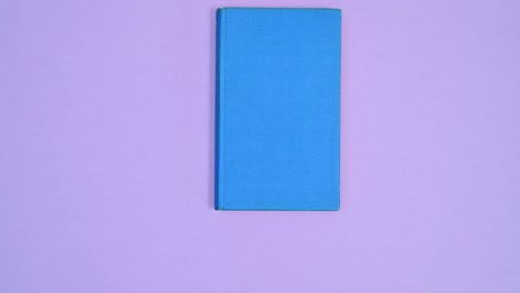 blue hardcover book moving on different sides of purple theme and open. stop motion flat lay