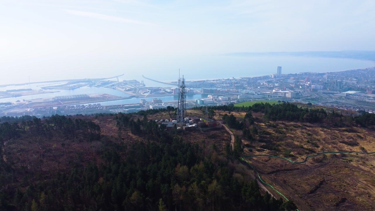 Aerial High Above TV Radio Transmitter Beaming Down to City Below with Hazy Atmosphere. Drone Clip Filmed in Swansea, UK.