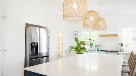 Video-of-modern,-domestic-kitchen-with-fridge-freezer,-hanging-lamps-over-central-island,-copy-space