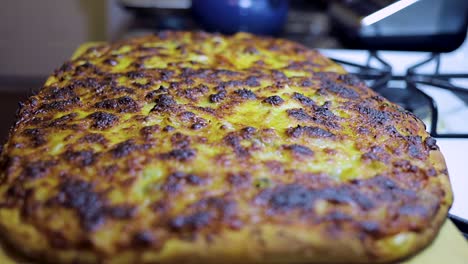 una mujer afroamericana está tomando una pizza casera recién horneada del horno en preparación para la cena