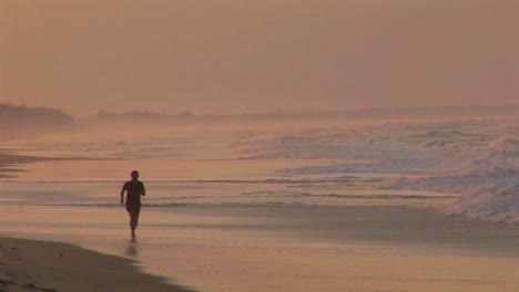 a man jogs along a beach in silhouette