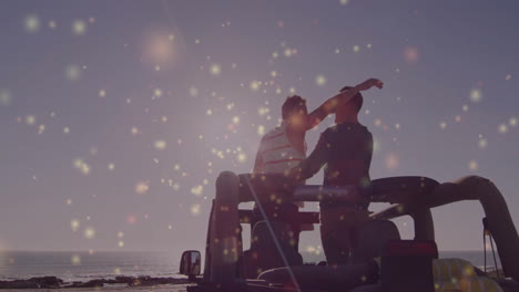 two men leaning together on jeep at rocky shoreline, showing travel lifestyle with bokeh sparkles