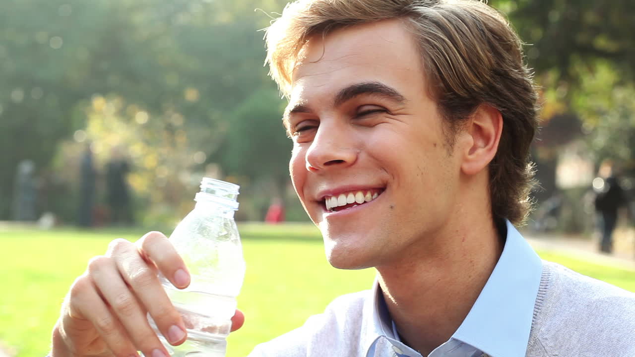 건강한 남자가 야외에서 물을 마시고 있습니다.