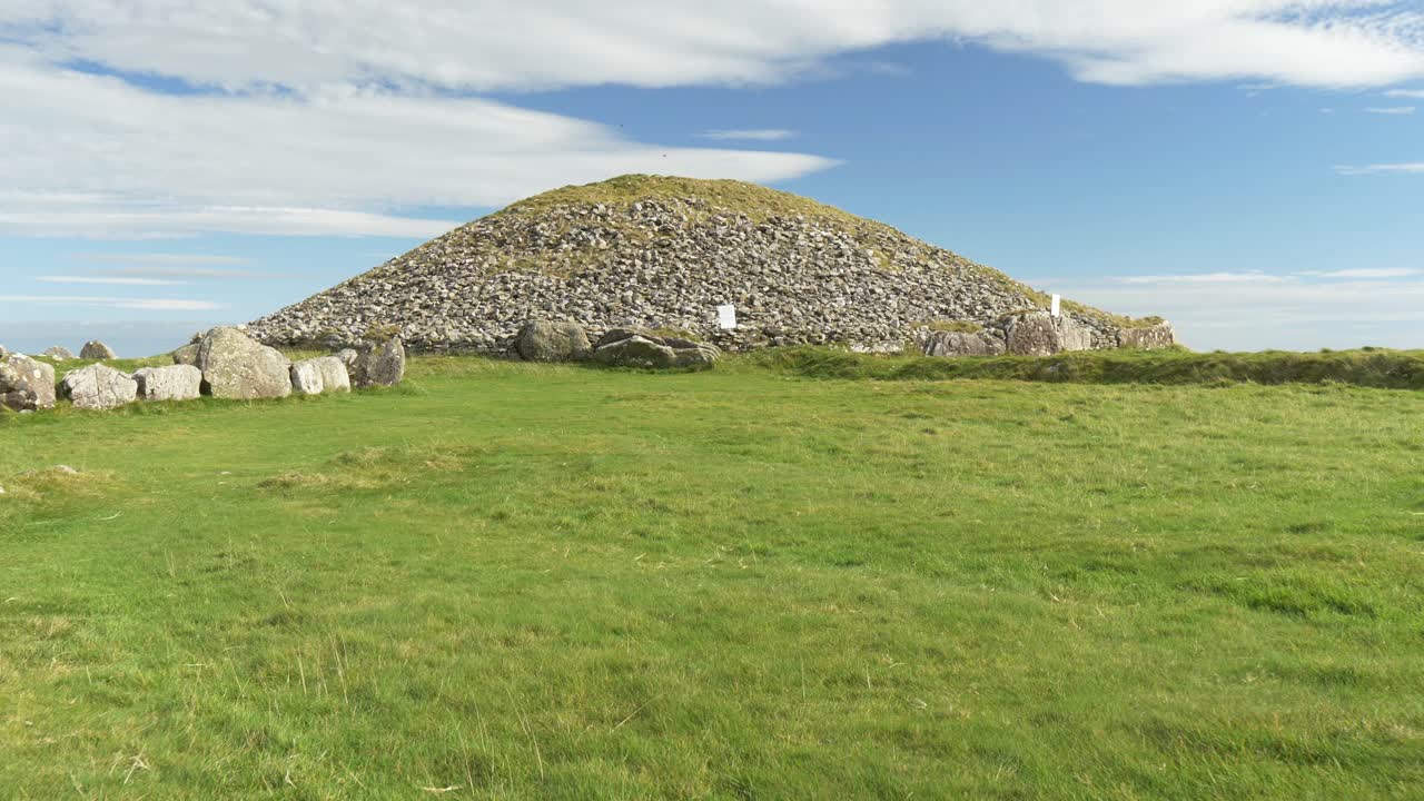 Oldtidsgrav i frodigt felt ved Loughcrew, Irland under en blå himmel