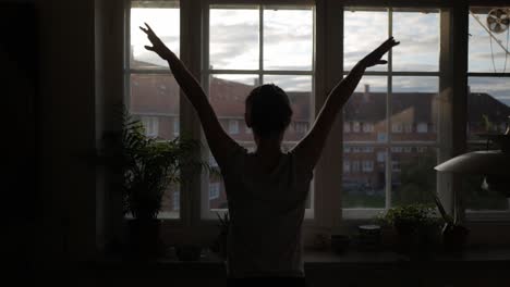 Woman-dancing,-exercise-in-front-of-apartment-window-in-the-morning