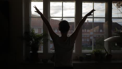 woman dancing, exercise in front of apartment window in the morning