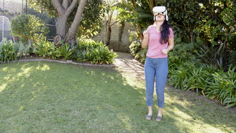 wearing vr headset, woman in garden with arms raised, enjoying virtual reality
