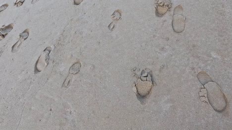 multiple shoe prints on sandy beach surface