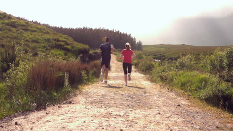 Pareja-En-Forma-Corriendo-En-El-Campo-Lejos-De-La-Cámara