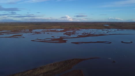 Aufsteigend-Eine-Antenne-über-Weite-Lagunen-Und-Landwirtschaftliche-Felder-Am-Horizont-Aufbauen,-Griechenland