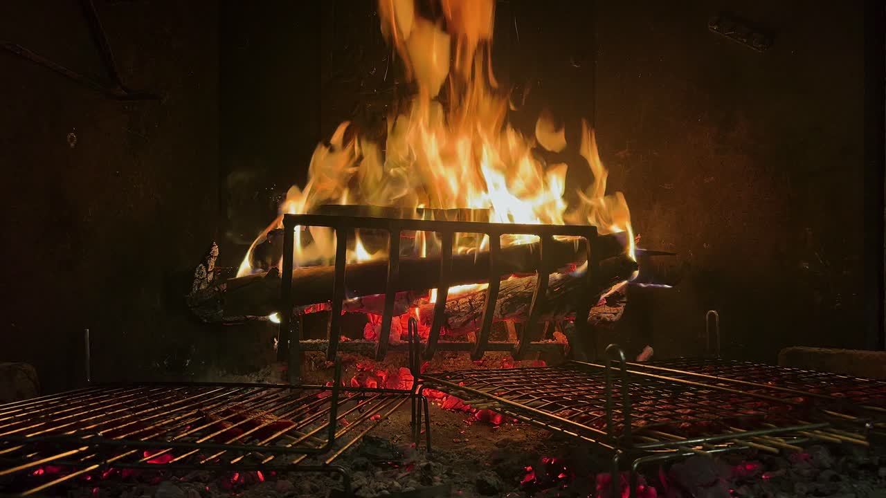 deliciosas salchichas y carne cocinada en la parrilla de la chimenea con fuego ardiendo en el fondo, primer plano