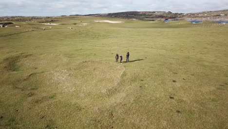 aerial view, three people on stand on a grassy field in connemara, ireland