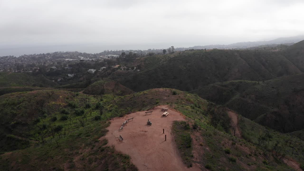 Aerial descending and panning shot of Inspiration Point at Will Rogers State Historic Park in the aftermath of the Palisades Fire in Los Angeles, California. 4K