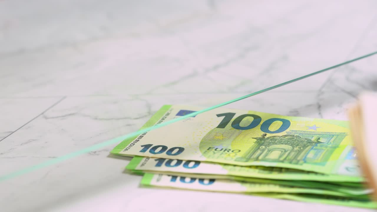 Person betaler penge til kassemedarbejder ved kassevindue, nærbillede. Veksler 50 og 100 eurosedler for at købe og sælge
