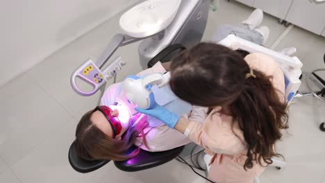 dentist providing professional teeth whitening using advanced equipment in modern dental office.