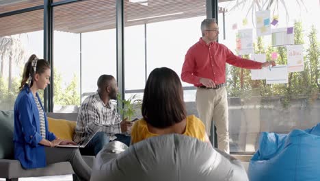 caucasian businessman discussing with his colleagues over memo notes on glass window at office