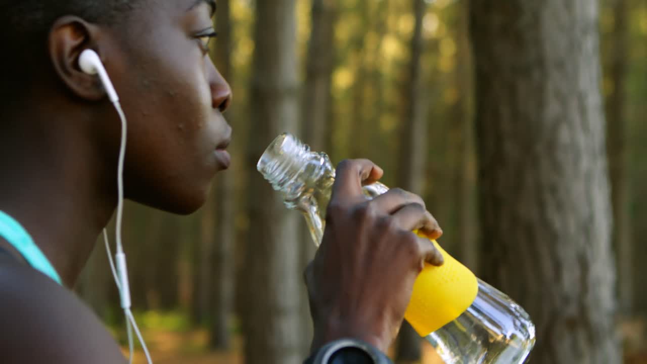una corredora bebiendo agua en el bosque 4k