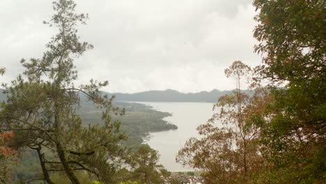 Luftaufnahme-Von-Kleinen-Ländlichen-Dörfern-Und-Landwirtschaftlichen-Feldern-Auf-Den-Hügeln-Unterhalb-Der-Hänge-Des-Mount-Batur-In-Bali,-Indonesien.-Kippende-Laibung-Des-Berges-Batur-Mit-Bewölktem-Gipfel