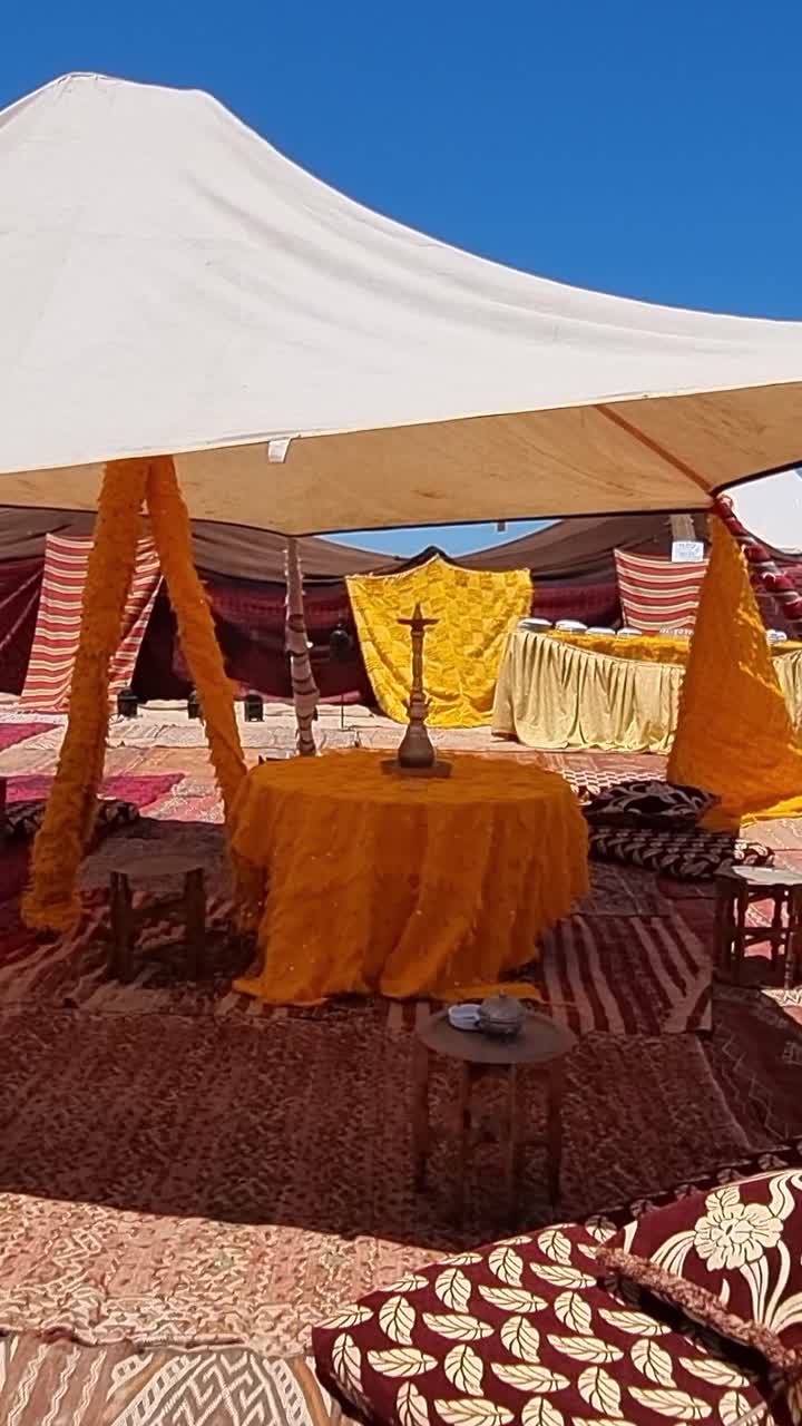 Autentica tenda berbera allestita per una tradizionale cerimonia del tè nel deserto del Sahara vicino a Tarfaya, Marocco, con arredi colorati.