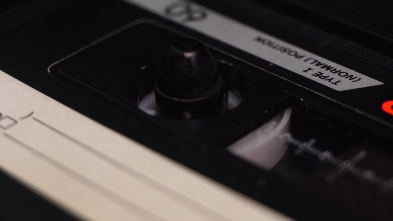 Inserimento e riproduzione di una registrazione su audiocassetta dall'inizio in un lettore vintage, primo piano macro