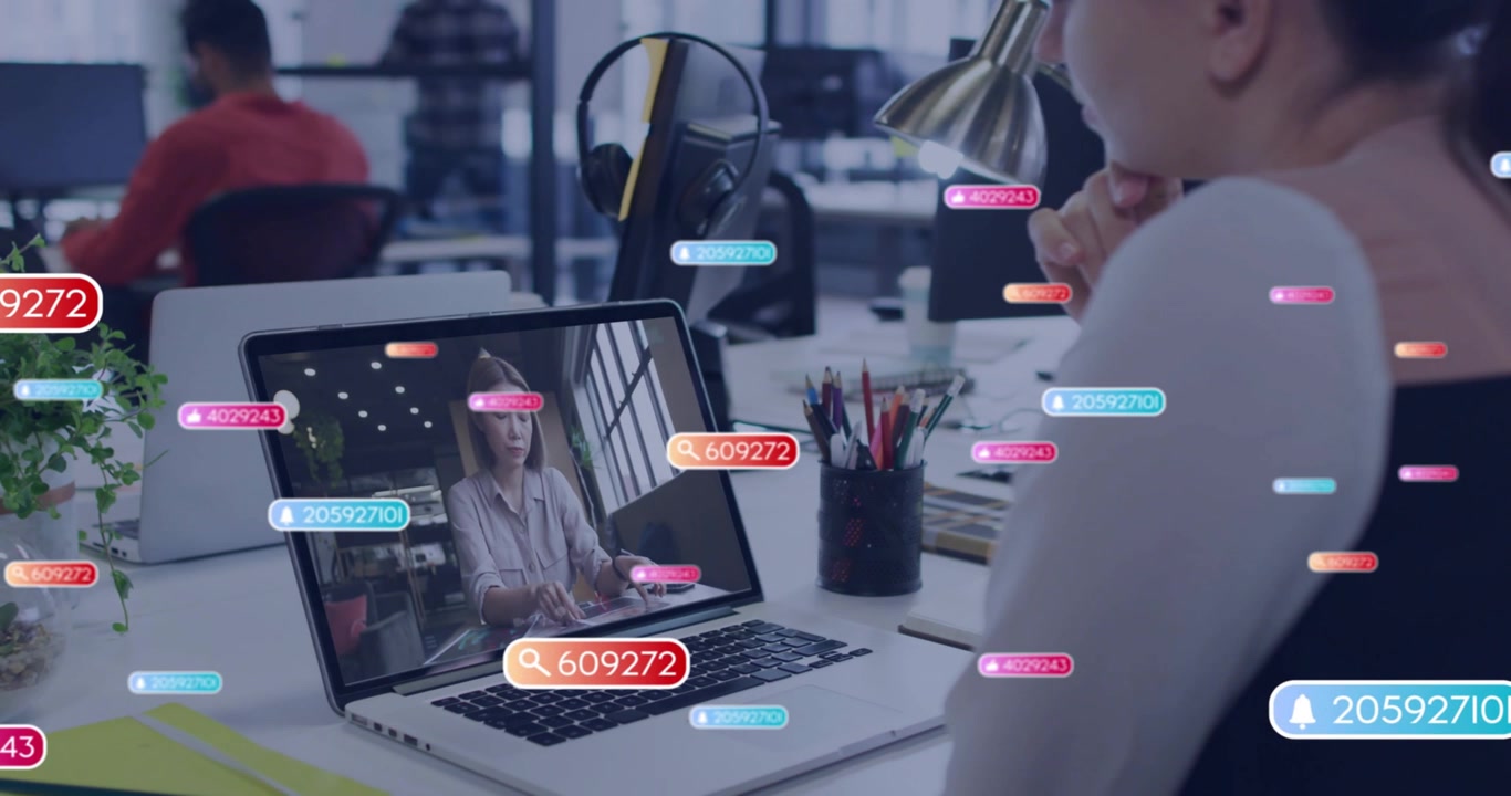 Worker observing business laptop call as presenter speaking, badges overlaying screen and desk