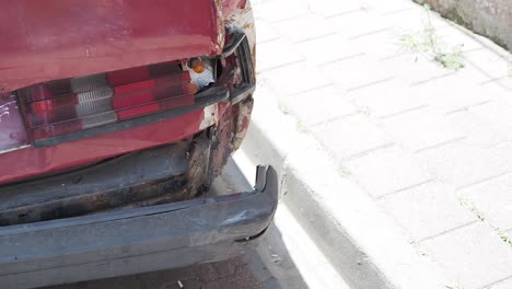 damaged red car on the side of the road