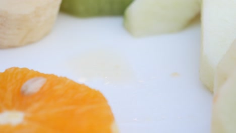 close-up of sliced orange, apple, and banana on a white plate