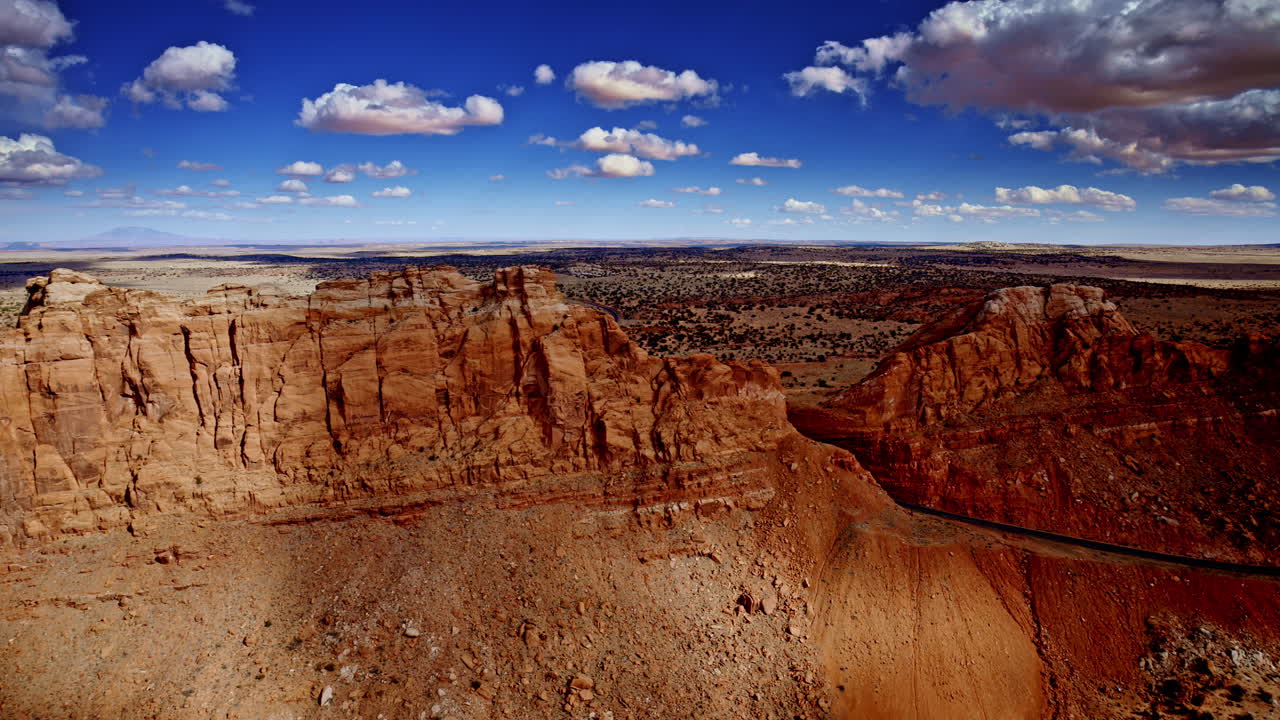 The drone glides overhead, capturing the grandeur of canyons, mesas, and rugged red rock terrain.