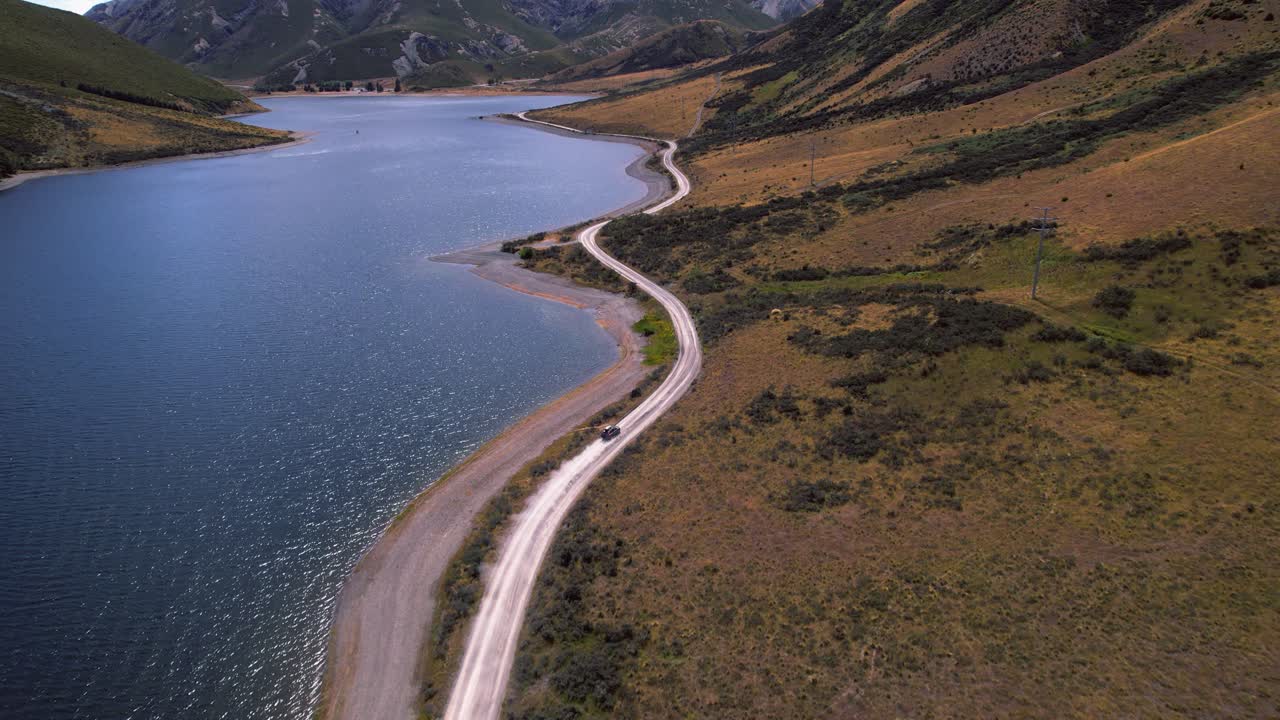 Aerial view following a car driving at Lake Lyndon, sunny day in New Zealand
