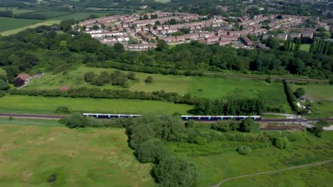 4K-drone-footage-tracking-a-blue-train-traveling-towards-Canterbury