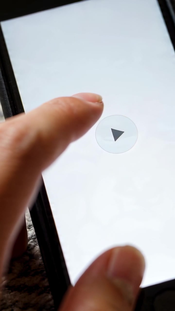 Video verticale: Un dito indice che preme l'icona di riproduzione del telefono a casa, testando la riproduzione.
