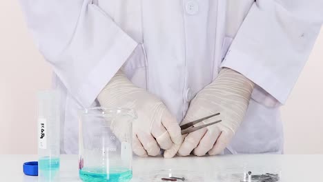 a scientist uses tweezers to manipulate metal pieces in a laboratory setting.