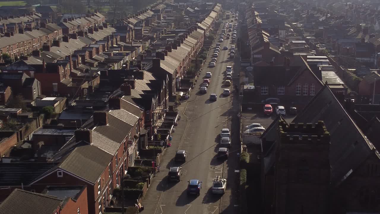 조감도는 dentons green에 있는 유서 깊은 계단식 주택의 행, 분주한 시내 중심가로 이어지는 긴 도로가 있는 st helens, 궤도를 도는 샷을 보여줍니다.