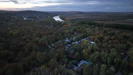 Acercándose-Con-Un-Dron-A-Un-Pueblo-Situado-Junto-Al-Río-Dniéster,-Escondido-En-El-Bosque-Alrededor-De-Los-árboles.