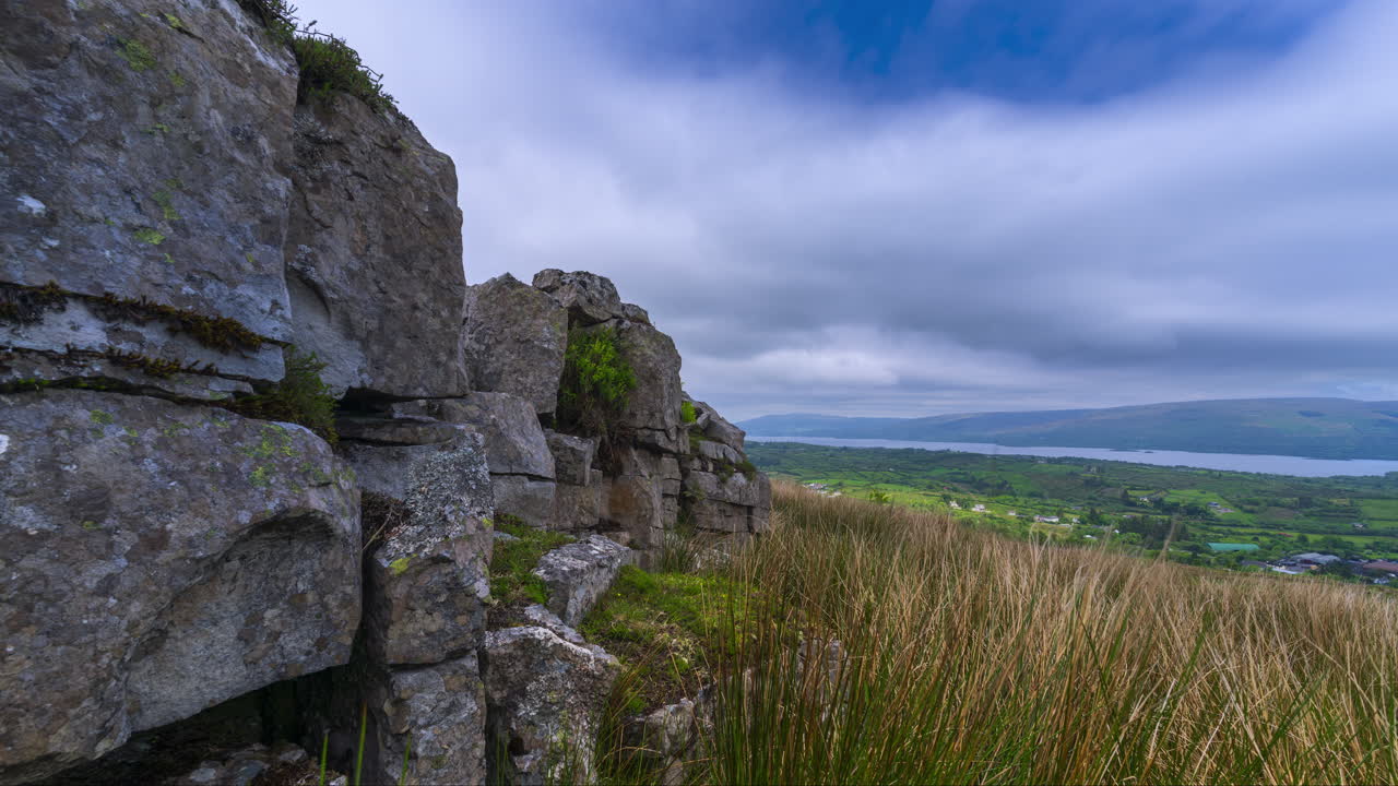 Time lapse of rural landscape with rocky foreground and hills and lake in the distance during a spring overcast cloudy day in Arigna mountains in county Leitrim in Ireland