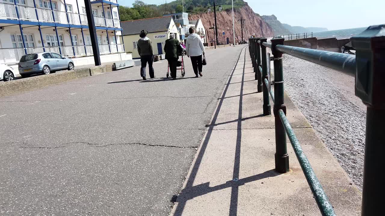 People walking on a seaside promenade next to cliffs and beach
