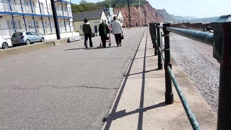 people walking on a seaside promenade next to cliffs and beach