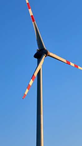 wind turbine spinning under clear sky. a large wind turbine rotates against a bright blue sky, harnessing renewable energy on a sunny day