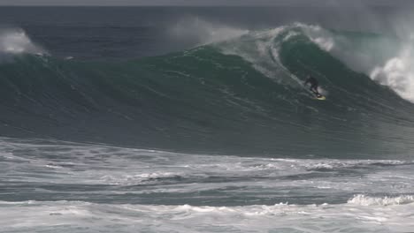 Surfista-Hábilmente-Zigzaguea-En-Una-Gran-Ola-Que-Rompe-Detrás-De-él-Y-Termina-Su-Viaje-Con-Un-Backflip